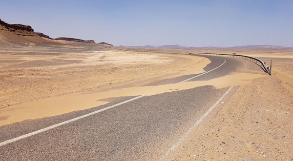 Sandverwehungen auf der Strasse in der Wüste